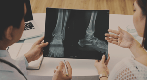 Arzthelferinnen mit einem Röntgenbild von Füßen in ihren Händen